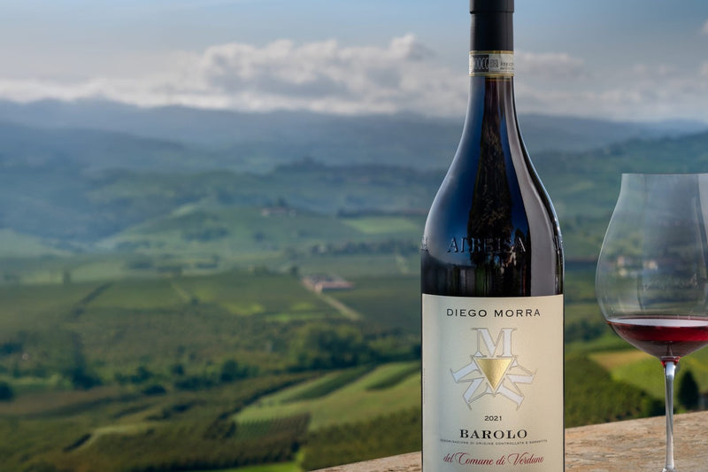 Fles Barolo del Comune di Verduno van Diego Morra op een muurtje met uitzicht over de heuvels van de Langhe
