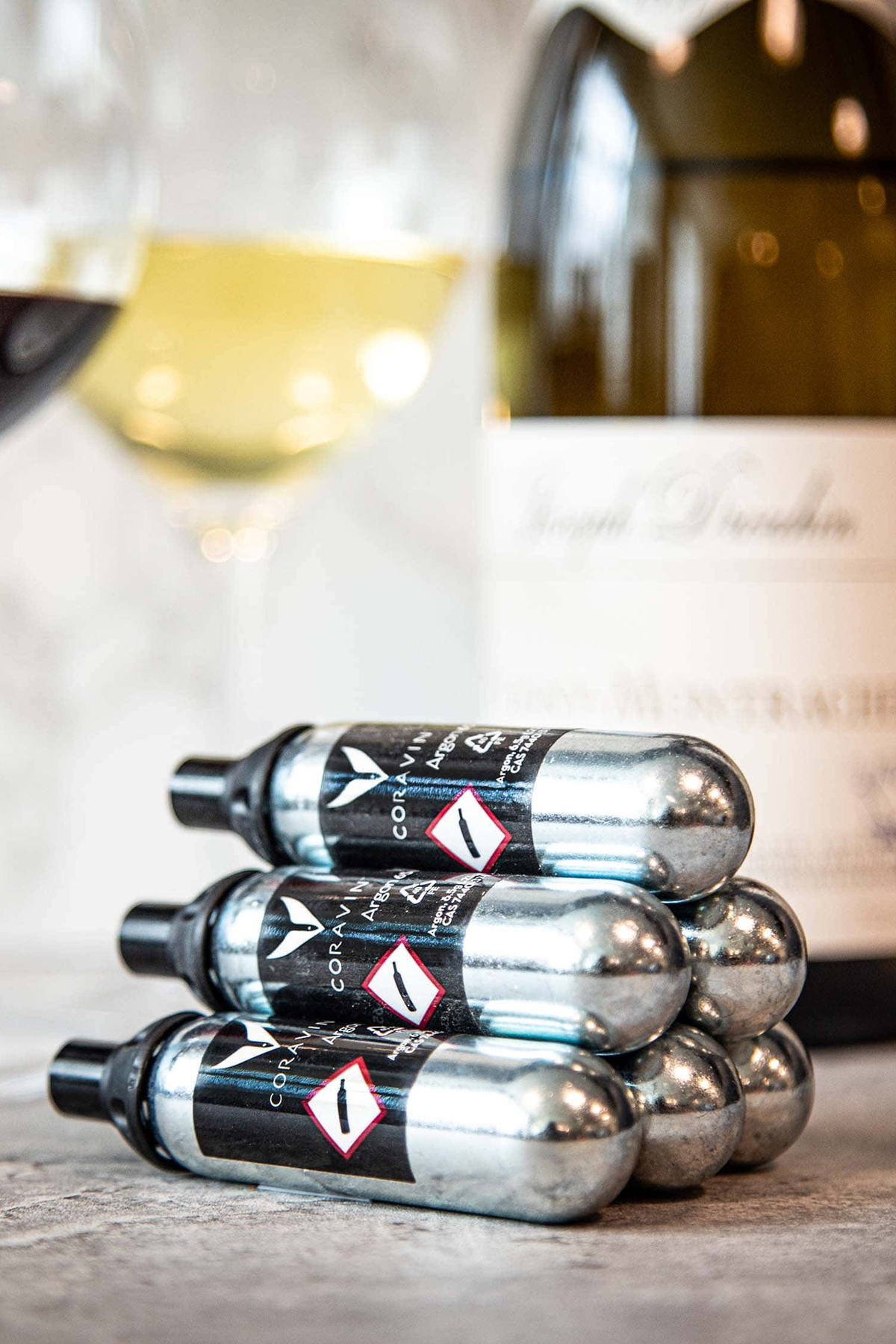 Coravin Pure argon-capsules met een wijnfles op de achtergrond
