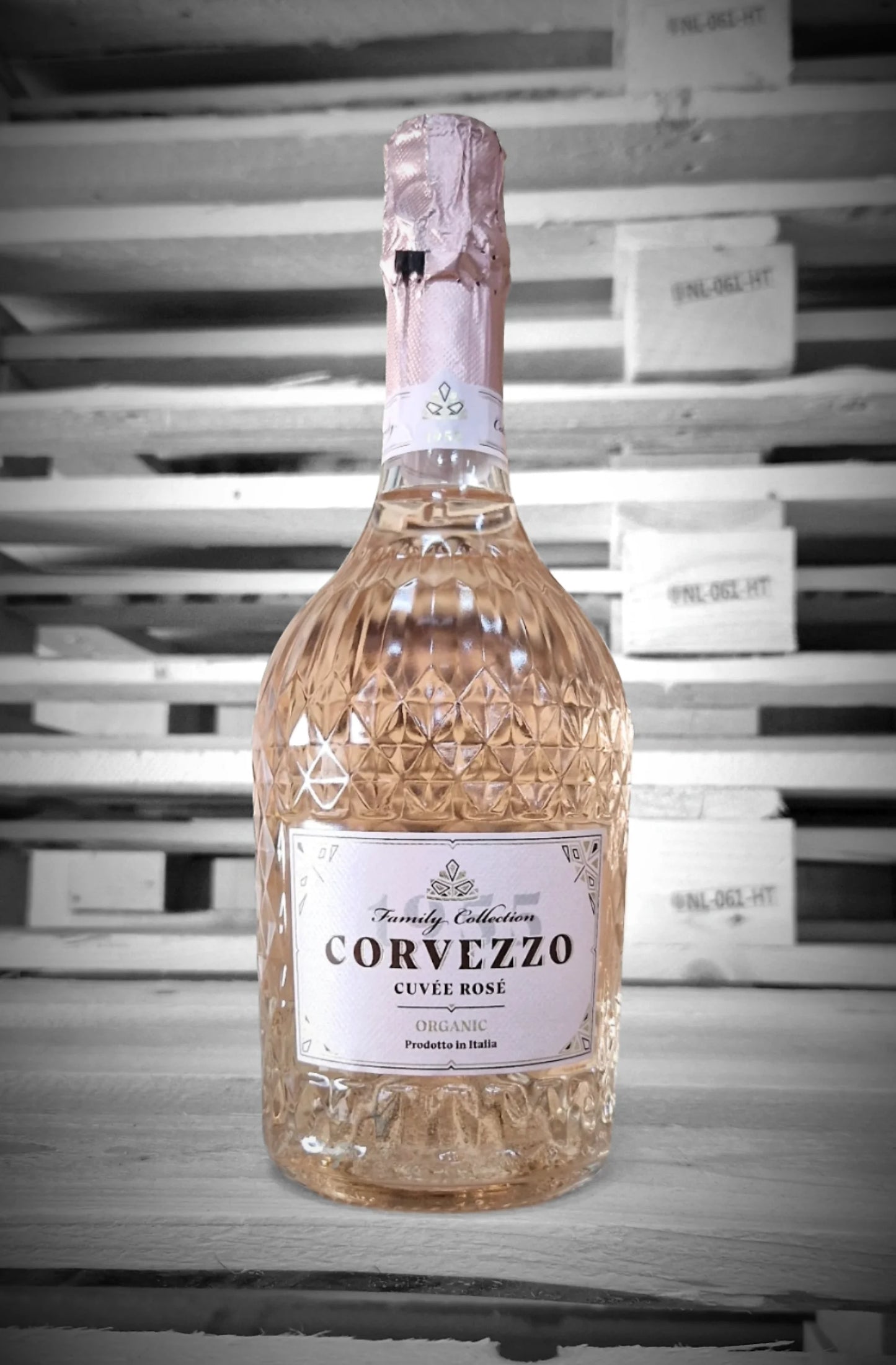 Fles Corvezzo Rosé Bubbel tegen vervaagde loodsachtergrond – Mixdoos D (6× Rosé Bubbel)